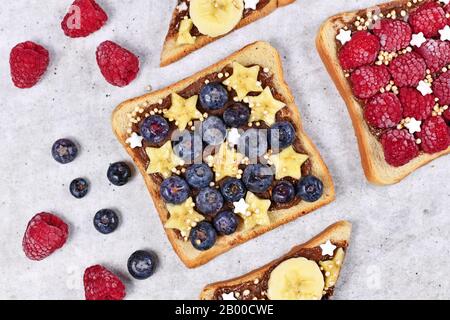 Cibo sano con fette di frutta farro pane tostato sormontato da mirtillo e banana e cereali quinoa soffiato Foto Stock