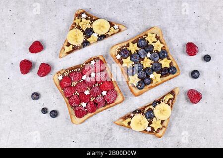 Cibo sano con fette di pane tostato farro condito con frutta come lampone rosso, mirtillo, banana e cereali di quinoa soffiato Foto Stock