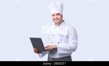 Chef Man Using Laptop Standing On White Studio Background, Panorama Foto Stock