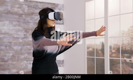 Bella casa designer femminile utilizzando occhiali realtà virtuale all'interno di un appartamento vuoto. Foto Stock