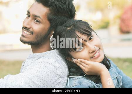 Giovani amici adolescenti che si godono ascoltare la canzone o la musica preferita Seduti indietro - Concetto di coppia rilassante, pic-nic nel parco, amore, datazione Foto Stock