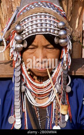 Thailandia: Donna Akha fumante pipe, mercato di Doi Mae Salong (Santikhiri) mattina presto, provincia di Chiang Rai. Gli Akha sono una tribù collinare di contadini di sussistenza noti per la loro arte. Il gruppo etnico potrebbe essere originario della Mongolia circa 1500 anni fa. La maggior parte delle persone Akha rimanenti sono ora distribuite in piccoli villaggi tra le montagne della Cina, del Laos, del Myanmar (Birmania) e della Thailandia settentrionale, dove sono una delle sei principali tribù di colline. Gli Akha iniziarono ad arrivare in Thailandia all'inizio del ventesimo secolo e continuarono ad emigrare, con circa 80,000 abitanti che ora vivono in Thailandia. Foto Stock