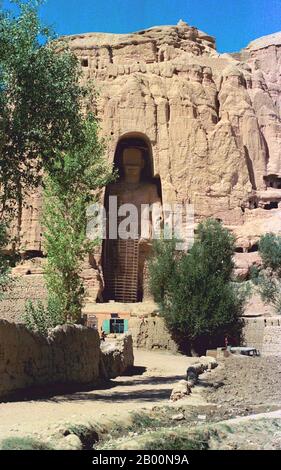 Afghanistan: Buddha di Bamiyan nel 1979. Foto di Andrew Forbes. I Buddha di Bamiyan erano due statue monumentali del VI secolo di Buddha in piedi scolpiti sul lato di una scogliera nella valle di Bamiyan nella regione di Hazarajat dell'Afghanistan centrale, situata a 230 km (143 miglia) a nord-ovest di Kabul ad un'altitudine di 2,500 metri (8,202 piedi). Costruite nel 507 d.C., le più grandi nel 554 d.C., le statue rappresentavano lo stile classico mescolato di Gandhara. I corpi principali erano scavati direttamente dalle scogliere di arenaria, ma i dettagli erano modellati in fango misto a paglia, ricoperti di stucco. Foto Stock