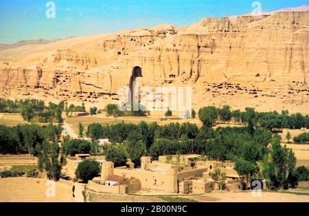 Afghanistan: Vale di Bamiyan nel 1979, con il più grande dei due Buddha Bamiyan a sinistra centro. Foto di Andrew Forbes. I Buddha di Bamiyan erano due statue monumentali del VI secolo di Buddha in piedi scolpiti sul lato di una scogliera nella valle di Bamiyan nella regione di Hazarajat dell'Afghanistan centrale, situata a 230 km (143 miglia) a nord-ovest di Kabul ad un'altitudine di 2,500 metri (8,202 piedi). Costruite nel 507 d.C., le più grandi nel 554 d.C., le statue rappresentavano lo stile classico mescolato di Gandhara. I corpi principali erano scavati direttamente dalle scogliere di arenaria. Foto Stock