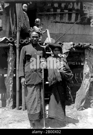 Indonesia: Una coppia di Batak del nord Sumatra in abbigliamento tradizionale, c.. 1915. Foto di Tassilo Adam (1878-1955)/Tropenmuseum (licenza CC BY-SA 3.0). Batak è un termine collettivo usato per identificare un certo numero di gruppi etnici trovati nel Nord Sumatra, Indonesia. Il termine è usato per includere il Toba, Karo, Pakpak, Simalungun, Angkola e Mandailing, ciascuno dei quali è distinto ma collegato gruppi con distinte, anche se correlate, lingue e costumi (adat). Occasionalmente è usato anche per includere il popolo Alas di Aceh centrale/meridionale, ma di solito solo per quanto riguarda i gruppi linguistici. Foto Stock