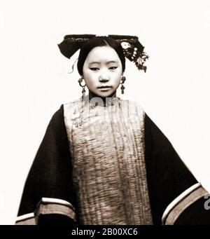 China: Coiffure Of A Tartar Or Manchu woman, Beijing. Photo by John Thomson (1837-1921), 1869.  Example of a coiffure on a Tartar or Manchu female, who is wearing a long sleeved quilted garment. The hair is wrapped around a flat strip of wood. Foto Stock