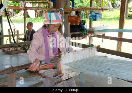 Thailandia: I tessitori siedono sotto una tradizionale casa della diga di Tai, Ban Na Pa Nat Tai Dam Villaggio Culturale, Provincia di Loei. La Diga di Tai o Tai Nero sono un gruppo etnico che si trova in alcune parti del Laos, Vietnam, Cina e Thailandia. I parlanti di Tai Dam in Cina sono classificati come parte della nazionalità dai insieme a quasi tutti gli altri popoli Tai. Ma in Vietnam loro viene data la propria nazionalità (con il Tai Bianco), dove sono classificati come la nazionalità Thái (che significa popolo Tai). La diga di Tai ha origine dalle vicinanze di Dien Bien Phu in Vietnam. Foto Stock
