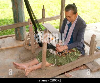 Thailandia: Un tessitore si trova sotto una tradizionale casa di Tai Dam, Ban Na Pa Nat Tai Dam Villaggio Culturale, Provincia di Loei. La Diga di Tai o Tai Nero sono un gruppo etnico che si trova in alcune parti del Laos, Vietnam, Cina e Thailandia. I parlanti di Tai Dam in Cina sono classificati come parte della nazionalità dai insieme a quasi tutti gli altri popoli Tai. Ma in Vietnam loro viene data la propria nazionalità (con il Tai Bianco), dove sono classificati come la nazionalità Thái (che significa popolo Tai). La diga di Tai ha origine dalle vicinanze di Dien Bien Phu in Vietnam. Foto Stock