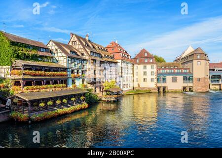 Edifici a graticcio e ex mulini ad acqua che costeggiano il fiume Ill nel quartiere Petite France a Strasburgo, Francia, in una mattinata di sole. Foto Stock