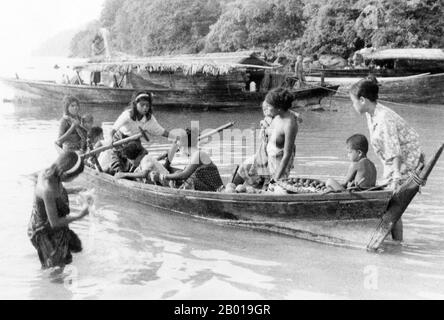 Thailandia: Chao Thalae 'Sea Gypsy' donne e bambini con barche, Phuket, c.. 1960. I «Sea Zingari» o Moken del Mare delle Andamane, noti in tailandese come chao Thalae o «popolo del mare», sono suddivisi in tre gruppi. Essi sono compresi tra il 4.000 e il 5.000, vivono solo sulla costa, sia in capanne a riva, o su imbarcazioni che collegano le acque costiere dall'arcipelago Mergui in Birmania alle isole Tarutao nel sud della Thailandia. Il più grande gruppo di gitani marini sono gli Urak Lawoi, che si aggirano intorno al 3.000. Vivono in semplici baracche sulle spiagge che si estendono a sud da Phuket alle Isole Tarutao. Foto Stock