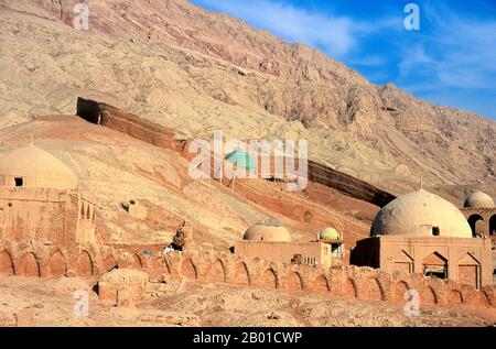 Cina: Uomini che lavorano su una tomba nel cimitero vicino al villaggio di Tuyoq vicino Turpan, provincia di Xinjiang. Tuyoq o Tuyugou è un'antica oasi-villaggio nel deserto di Taklamakan, 70 km a est di Turpan in una valle lussureggiante che si estende nelle Flaming Mountains, con un ben conservato orientamento Uyghur. E' famosa per le sue uve senza semi e per un certo numero di antiche grotte di meditazione buddista nelle vicinanze contenenti affreschi, la piu' conosciuta essendo le Grotte dei Mille Buddha di Bezeklik. Foto Stock