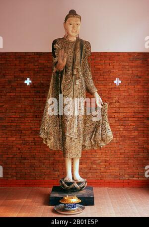 Thailandia: Figura di Buddha in piedi, Wat Prasat, Chiang mai. Wat Prasat (วัดปราสาท) risale almeno al 16th° secolo, ed è probabilmente ancora più vecchio. L'edificio più importante del complesso del tempio è l'antico viharn, che risale al 1823 ma è stato ristrutturato con gusto nel 1987. Costruito nel tradizionale e distintivo stile LAN Na, il viharn e' costruito con pannelli di legno di teak abilmente lavorati su una base di mattoni e stucco imbiancati. L'ingresso principale, che naturalmente si affaccia ad est, è raggiunto da una bassa rampa di gradini fiancheggiata dalle balaustre di naga. Foto Stock