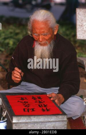 Vietnam: Artista di Calligraphy con una lunga barba bianca vicino al lago ho Hoan Kiem, Hanoi. La calligrafia dell'Asia orientale è una forma di calligrafia ampiamente praticata e venerata nella Sinosfera. Ciò include più spesso la Cina, il Giappone, la Corea ed il Vietnam. La tradizione calligrafica dell'Asia orientale è nata e sviluppata dalla Cina. Esiste una standardizzazione generale dei vari stili di calligrafia in questa tradizione. La calligrafia asiatica orientale e la pittura dell'inchiostro e del lavaggio sono strettamente collegate, poiché compiute usando gli attrezzi e le tecniche simili. Foto Stock