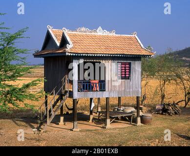 Cambogia: Una casa palafitte dipinta di blu sulle pianure centrali della Cambogia, una vista comune in tutto il paese. In epoca angkoriana la gente più comune viveva in case a palafitte con scale in legno che portavano ad un unico piano. Sotto la casa, donne tessute e animali domestici al riparo. I rifiuti umani sono stati comunemente depositati attraverso i fori nelle tavole da pavimento per la gratitudine dei maiali e dei cani della famiglia qui sotto. Foto Stock