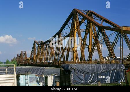 Vietnam: Il lungo ponte Bien, Hanoi. Il ponte Long Bien fu eretto dai colonialisti francesi tra il 1899 e il 1902 e nominato ponte Paul Doumer in onore dell'allora governatore dell'Indochina francese (1897-1902). È stato progettato e costruito da Dayde e Pille di Parigi (le placche originali sono ancora in atto) ed è lungo 1.682 metri (5.518 piedi), composto da 18 campate, con un'ulteriore estensione centrale allungata di 106 metri (347 piedi). Trasporta l'unica linea ferroviaria tra Hanoi e Haiphong, così come due collegamenti ferroviari vitali con la Cina. Foto Stock