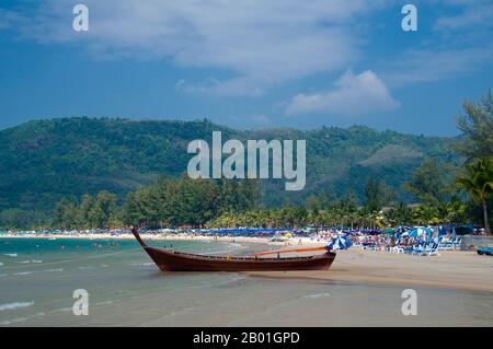 Thailandia: Barca e ombrelloni colorati, Hat Kamala (Kamala Beach), Phuket. Phuket, a 810 kmq, l'isola piu' grande della Tailandia, si trova nel Mare delle Andamane, appena al largo della costa della Provincia di Phang-nga. Unito alla terraferma da un'ampia strada rialzata, si e' sviluppato nel piu' lussuoso e squisito resort sulla spiaggia della Tailandia. Nei secoli passati Phuket era un importante centro commerciale sulla costa orientale della baia del Bengala, che si occupava della navigazione e dei marinai dei mondi arabi e malesi, dell'India, del Myanmar, della Cina e, naturalmente, Siam. Nel XVI secolo l'isola era ben nota anche agli europei. Foto Stock