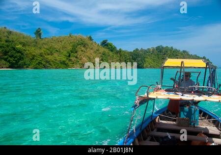 Thailandia: Barcaiolo e mare turchese, Ko Kradan, provincia di Trang. Ko Kradan si trova a 13 km (8 miglia) a sud del molo Pak Meng di Trang ed è solo una delle perle del Mare delle Andamane che si trovano al largo della costa sud-occidentale di Trang. La provincia di Trang dipendeva dall'estrazione dello stagno fino a quando le prime piantine di gomma furono portate in Thailandia intorno al 1901 - parte di un lungo viaggio dal Sud America attraverso i vicini stati malesi. La gomma, l'olio di palma e la pesca sono i pilastri dell'economia della provincia. Il turismo sta avendo un impatto crescente poiché la costa di Anadaman e le isole di Trang sono sempre più sviluppate e diffuse. Foto Stock