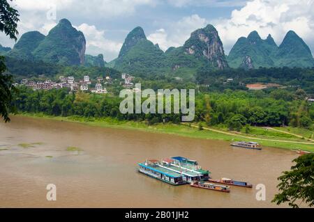 Cina: Barche sul fiume li a Yangshuo, vicino a Guilin, provincia del Guangxi. Yangshuo è giustamente famosa per i suoi paesaggi suggestivi. Si trova sulla riva occidentale del fiume li (Lijiang) ed è a soli 60 km a valle di Guilin. Negli ultimi anni è diventata una destinazione popolare tra i turisti pur mantenendo la sua atmosfera di piccola città fluviale. Guilin è la scena dei paesaggi più famosi della Cina, ispirando migliaia di dipinti nel corso di molti secoli. Le "montagne e fiumi più belli sotto il cielo" sono così stimolanti che poeti, artisti e turisti hanno reso questa attrazione naturale numero uno della Cina. Foto Stock