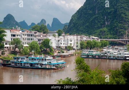 Cina: Barche sul fiume li a Yangshuo, vicino a Guilin, provincia del Guangxi. Yangshuo è giustamente famosa per i suoi paesaggi suggestivi. Si trova sulla riva occidentale del fiume li (Lijiang) ed è a soli 60 km a valle di Guilin. Negli ultimi anni è diventata una destinazione popolare tra i turisti pur mantenendo la sua atmosfera di piccola città fluviale. Guilin è la scena dei paesaggi più famosi della Cina, ispirando migliaia di dipinti nel corso di molti secoli. Le "montagne e fiumi più belli sotto il cielo" sono così stimolanti che poeti, artisti e turisti hanno reso questa attrazione naturale numero uno della Cina. Foto Stock