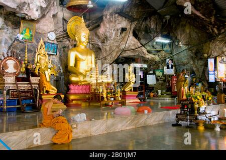 Thailandia: Monaci, Wat Tham Seua, città di Krabi, provincia di Krabi, Thailandia meridionale. Wat Tham Seua, il "Tempio della Grotta della Tigre" è costruito in una grotta posta su una scogliera calcarea. Circondato da residenze individuali dei monaci, questo è uno dei templi forestali più noti della Thailandia meridionale. Il viharn principale o sala delle assemblee si estende in una lunga e poco profonda grotta calcarea che mostra vari oscuri ricordi della mortalità come contrappeso ai desideri mondani. Sul retro della grotta una rampa di scale di marmo conduce alla "grotta della tigre" stessa. All'interno c'è una venerata impronta di Buddha su una piattaforma dorata. Foto Stock