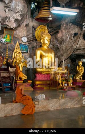 Thailandia: Monk, Wat Tham Seua, Krabi Town, Krabi Province, Thailandia meridionale. Wat Tham Seua, il "Tempio della Grotta della Tigre" è costruito in una grotta posta su una scogliera calcarea. Circondato da residenze individuali dei monaci, questo è uno dei templi forestali più noti della Thailandia meridionale. Il viharn principale o sala delle assemblee si estende in una lunga e poco profonda grotta calcarea che mostra vari oscuri ricordi della mortalità come contrappeso ai desideri mondani. Sul retro della grotta una rampa di scale di marmo conduce alla "grotta della tigre" stessa. All'interno c'è una venerata impronta di Buddha su una piattaforma dorata. Foto Stock