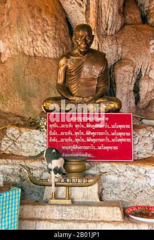 Thailandia: Statua Abate, Wat Tham Seua, città di Krabi, provincia di Krabi, Thailandia meridionale. Wat Tham Seua, il "Tempio della Grotta della Tigre" è costruito in una grotta posta su una scogliera calcarea. Circondato da residenze monache individuali, questo è uno dei templi forestali più noti della Thailandia meridionale. Il viharn principale o sala di assemblaggio si estende in una lunga grotta calcarea poco profonda che mostra vari tristi ricordi della mortalità come controbilanciamento ai desideri mondani. Sul retro della grotta una rampa di scale di marmo conduce alla "grotta della tigre" stessa. Foto Stock