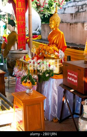 Thailandia: Statua del Buddha di fronte al chedi a Wat Duang di, Chiang mai. Il Wat Duang di o 'Monastero della buona fortuna' risale al XIX secolo ed è famoso per i suoi frontoni scolpiti e altre decorazioni in stucco. Re Mengrai fondò la città di Chiang mai (che significa "nuova città") nel 1296, e succedette a Chiang Rai come capitale del regno Lanna. Chiang mai, talvolta scritta come "Chiengmai" o "Chiangmai", è la città più grande e culturalmente significativa del nord della Thailandia. Foto Stock