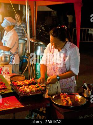 Thailandia: Venditore di kebab al mercato domenicale accanto alla stazione ferroviaria, Trang Town, Trang Province, Thailandia meridionale. Trang è stato un centro commerciale almeno dal i secolo d.C. Crebbe fino alla prosperità tra il VII e il XIII secolo durante il periodo Srivijaya e rimane oggi un'importante città commerciale. Gomma, olio di palma e pesca sono i pilastri dell'economia cittadina. Il turismo sta avendo un impatto crescente poiché la costa delle Andamane e le isole di Trang sono sempre più sviluppate e diffuse. Foto Stock