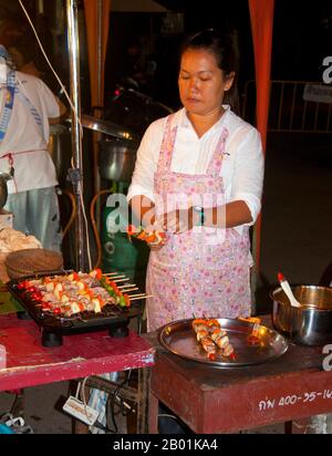 Thailandia: Venditore di kebab al mercato domenicale accanto alla stazione ferroviaria, Trang Town, Trang Province, Thailandia meridionale. Trang è stato un centro commerciale almeno dal i secolo d.C. Crebbe fino alla prosperità tra il VII e il XIII secolo durante il periodo Srivijaya e rimane oggi un'importante città commerciale. Gomma, olio di palma e pesca sono i pilastri dell'economia cittadina. Il turismo sta avendo un impatto crescente poiché la costa delle Andamane e le isole di Trang sono sempre più sviluppate e diffuse. Foto Stock