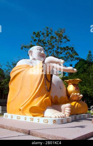 Thailandia: Statua di Phra Sangkajjayana (Buddha che ride o Budai), Wat Matchimaphum, città di Trang, provincia di Trang, Thailandia meridionale. Budai, pronunciato Hotei in giapponese e Bố Đại in vietnamita, è una divinità folcloristica cinese. Il suo nome significa "sacco di stoffa" e deriva dalla borsa che è tradizionalmente raffigurata come portatrice. Di solito è identificato con (o come incarnazione di) Buddha Maitreya, tanto che l'immagine di Budai è una delle forme principali in cui il Buddha Maitreya è raffigurato in Asia orientale. È quasi sempre mostrato sorridere o ridere, da qui il suo soprannome cinese, il Buddha ridendo Foto Stock