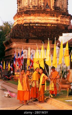 Thailandia: Monaci che svelano bandiere per un festival imminente davanti al chedi del XVI secolo a Wat Lok moli, Chiang mai, Thailandia settentrionale. Si pensa che Wat Lok moli o "topknot del mondo" sia stato fondato da re Ku Na, sesto re della dinastia Mangrai (1263-1578), che governò il regno di LAN Na da Chiang mai tra il 1367 e il 1388 circa. Probabilmente era un tempio reale, poiché il lato settentrionale della città era un distretto reale all'epoca; certamente il santuario godeva di una lunga e stretta associazione con i governanti Mangrai. Foto Stock