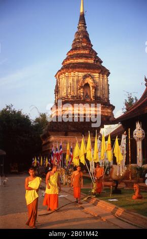 Thailandia: Monaci che svelano bandiere per un festival imminente davanti al chedi del XVI secolo a Wat Lok moli, Chiang mai, Thailandia settentrionale. Si pensa che Wat Lok moli o "topknot del mondo" sia stato fondato da re Ku Na, sesto re della dinastia Mangrai (1263-1578), che governò il regno di LAN Na da Chiang mai tra il 1367 e il 1388 circa. Probabilmente era un tempio reale, poiché il lato settentrionale della città era un distretto reale all'epoca; certamente il santuario godeva di una lunga e stretta associazione con i governanti Mangrai. Foto Stock