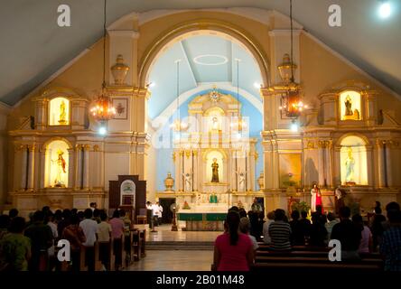 Filippine: Un servizio si svolge a St. William's Cathedral, Laoag, Ilocos Norte, Luzon Island. St La Cattedrale di Guglielmo, nota anche come Cattedrale di Laoag, fu originariamente costruita nel 1612 dai frati agostiniani per sostituire una cappella di legno. È noto per il suo design rinascimentale italiano e per il suo campanile che affonda nel terreno ad un ritmo di un pollice all'anno. Laoag (Ilocano per "luce o chiarezza"), è un antico e fiorente insediamento conosciuto dai commercianti cinesi e giapponesi quando il conquistador spagnolo Juan de Salcedo arrivò sulle rive settentrionali del fiume Padsan nel 1572. Foto Stock