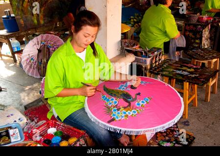 Thailandia: Decorare l'ombrello, Bo Sang Umbrella Village, vicino a Chiang mai, Thailandia settentrionale. Bo Sang, vicino alla città tailandese settentrionale di Chiang mai, è famosa per i suoi ombrelli e ombrelli dai colori vivaci fatti a mano. Una volta all'anno, alla fine di gennaio, nella città si tiene il Bo Sang Umbrella e il San Kamphaeng Handicrafts Festival. Chiang mai (che significa "città nuova"), a volte scritta come "Chiengmai" o "Chiangmai", è la città più grande e culturalmente significativa nel nord della Thailandia. Re Mengrai fondò la città di Chiang mai nel 1296, e succedette a Chiang Rai come capitale. Foto Stock
