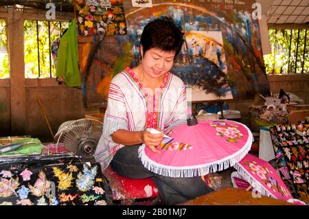 Thailandia: Decorare l'ombrello, Bo Sang Umbrella Village, vicino a Chiang mai, Thailandia settentrionale. Bo Sang, vicino alla città tailandese settentrionale di Chiang mai, è famosa per i suoi ombrelli e ombrelli dai colori vivaci fatti a mano. Una volta all'anno, alla fine di gennaio, nella città si tiene il Bo Sang Umbrella e il San Kamphaeng Handicrafts Festival. Chiang mai (che significa "città nuova"), a volte scritta come "Chiengmai" o "Chiangmai", è la città più grande e culturalmente significativa nel nord della Thailandia. Re Mengrai fondò la città di Chiang mai nel 1296, e succedette a Chiang Rai come capitale. Foto Stock