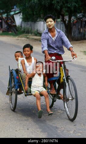 Birmania/Myanmar: Tre bambini di Bamar che cavalcano un risciò in bicicletta, il volto del conducente protetto dalla polvere di thanaka. I Bamar, chiamati anche Burman, sono il gruppo etnico dominante della Birmania (Myanmar), che costituisce circa i due terzi della popolazione. I Bamar vivono principalmente nel bacino dell'Irrawaddy e parlano la lingua birmana, che è anche la lingua ufficiale della Birmania. Le usanze e l'identità di Bamar sono strettamente intrecciate con le abitudini e l'identità birmane generali. I Bamar sono spesso, ma inaccurati, chiamati birmani. Foto Stock