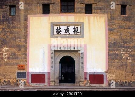 Cina: L'unico ingresso nella torre Zhenchang Lou Hakka vicino a Hukeng, contea di Yongding, provincia del Fujian. Gli Hakka (Kejia in mandarino; letteralmente "ospiti") sono cinesi Han che parlano la lingua Hakka. Le loro caratteristiche case di terra o tulou si trovano nelle contee di confine dove si incontrano le province di Guangdong, Jiangxi e Fujian. Le entità comuni, tulou, sono fortificate contro i banditi saccheggianti e generalmente fatte di terra compatta, bambù, legno e pietra. Contengono molte stanze su diversi piani, in modo che diverse famiglie possano vivere insieme. Foto Stock