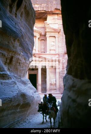 Giordania: The Siq (Shaft) e al Khazneh (The Treasury) in background, Petra. Il Siq o al-Siq ("il pozzo") è l'ingresso principale dell'antica città di Petra nel sud della Giordania. La dim e stretta gola (in alcuni punti non più di 3 metri di larghezza) si snoda per circa un miglio e termina alla rovina più elaborata di Petra, al Khazneh (il Tesoro). Petra fu fondata come città dagli arabi nabatei nel IV secolo a.C. e doveva la sua nascita e prosperità al fatto che era l'unico luogo con acqua chiara e abbondante tra i centri commerciali Hijaz della Mecca e Medina. Foto Stock