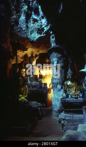 Thailandia: Un raggio di luce solare illumina le figure di Buddha raccolte all'interno delle grotte di Doi Chiang Dao (montagna di Chiang Dao), Chiang Dao, Thailandia settentrionale. Situato a 70 chilometri a nord di Chiang mai (Thailandia settentrionale) sulla strada per Fang, Chiang Dao si trova al riparo sotto l'impressionante mole di Doi Chiang Dao, un massiccio affioramento di roccia che si innalza ripidamente sulla città fino a un'altezza di 2.175 metri. La vetta, la terza più alta della Thailandia, è di solito avvolta da nuvole ed è sede di numerosi villaggi delle tribù collinari, tra cui gli insediamenti di Lisu, Lahu e Karen. Foto Stock