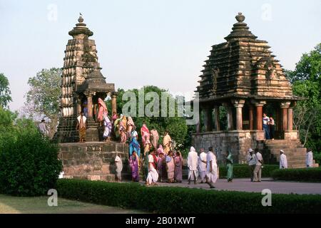 India: Un gruppo di pellegrini indù che visitano i templi del complesso occidentale di Khajuraho, Khajuraho, stato del Madhya Pradesh. Durante il X e l'XI secolo, i re Chandella dell'India centrale, le eredi di un potente clan Rajput che rivendicava la luna come loro antenato diretto, costruirono un totale di 85 templi per la gloria di Dio, la creazione e il pantheon indù. I Chandellas erano devoti indù. Eclissati dalla conquista moghul, dall'ascesa di dinastie rivali e dal passare del tempo, i templi languirono sotto il sole duro e le piogge monsoniche dell'India centrale, perdendo gradualmente nella giungla. Foto Stock