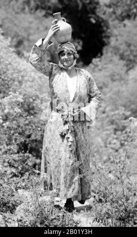 Palestina: Una giovane donna palestinese in posa con una bottiglia d'acqua sulla testa, Nazareth, 1910 circa. Palestina è un nome dato alla regione geografica tra il Mar Mediterraneo e il fiume Giordano. La regione è anche conosciuta come la Terra di Israele, la Terra Santa e il Levante meridionale. Nel 1832 la Palestina fu conquistata dall'Egitto di Muhammad Ali, ma nel 1840 la Gran Bretagna intervenne e restituì il controllo del Levante agli ottomani in cambio di ulteriori capitolazioni. La fine del XIX secolo vide l'inizio dell'immigrazione sionista e la rinascita della lingua ebraica. Foto Stock