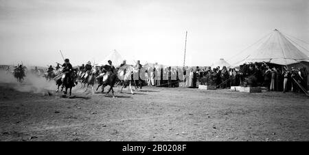 Arabia: Corse di cavalli beduine a un matrimonio nel deserto, c. 1900-1920. I beduini fanno parte di un gruppo etnico arabo che abita prevalentemente nel deserto tradizionalmente diviso in tribù, o clan, conosciuti in arabo come ʿašāʾir. Il termine "beduino" deriva da una forma plurale della parola araba badawī, in quanto è pronunciata nei dialetti colloquiali. Il termine arabo badawī deriva dalla parola bādiyah, che significa deserto semiarido (al contrario di ṣaḥarāʾ che significa deserto). A partire dalla fine del XIX secolo, molti beduini sotto il dominio britannico iniziarono a transitare verso una vita seminomadica. Foto Stock