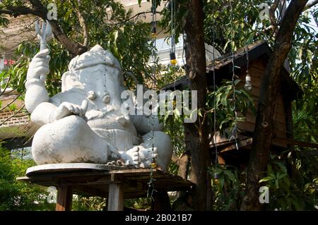 Bangkok: Figura di Ganesh nel giardino del Teatro Patravadi, Bangkok. Ganesha, scritto anche Ganesa o Ganesh, e noto anche come Ganapati, Vinayaka e Pillaiyar, è una delle divinità più conosciute e più ampiamente venerate nel pantheon indù. La sua immagine si trova in India e Nepal. Le sette indù lo adorano indipendentemente dalle affiliazioni. La devozione a Ganesha è ampiamente diffusa e si estende ai giainisti, ai buddisti e oltre l'India. Il Teatro Patravadi, sul lato Thonburi del fiume Chao Phraya di Bangkok, è famoso per le sue eccellenti esibizioni di musica e danza siamese. Foto Stock