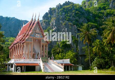 Thailandia: Tempio buddista all'interno del Parco nazionale di Khao Sam ROI Yot, provincia di Prachuap Khiri Khan. Khao Sam ROI Yot è diventato il primo parco nazionale costiero della Thailandia nel 1996. Copre un'area di circa 100 chilometri quadrati (40 miglia quadrate) tra cui ripide montagne calcaree disseminate di grotte, paludi, paludi di mangrovie, spiagge sabbiose e acque marine poco profonde lungo la costa. Il nome sam roi yot significa "trecento picchi" e questo si riferisce direttamente ai numerosi affioramenti e picchi calcarei che caratterizzano il parco, che si innalzano drammaticamente fino ad altezze superiori a 650 metri (2.150 piedi) Foto Stock