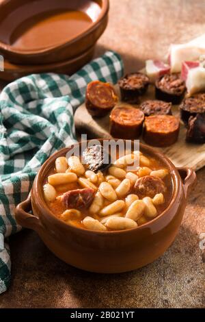 Tipica fabada asturiana spagnola in cockpot su tavola di legno Foto Stock