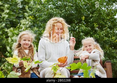 Madre single felice con due bambini in autunno nel giardino Foto Stock