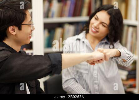 Coppia allegra che fa un gesto frettoloso nella biblioteca Foto Stock