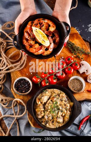 Gran fritto di gamberi in salsa di pomodoro con olio di oliva,funghi in salsa di panna julienne, champignon, prodotti per la cottura sul tavolo di legno sfondo Foto Stock