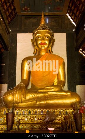 Thailandia: Immagine di Buddha nel viharn, Wat Pa Daet, Mae Chaem, Provincia di Chiang mai. Wat Pa Daet; il nome - "bosco illuminato dal sole" - indica che in passato era un tempio della foresta. Un recinto murato contiene un viharn, sala e ho trai o biblioteca, mentre appena fuori si trova un ubosot in stile tradizionale settentrionale, circondato da uno stretto fossato. Il viharn risale al 1877 ed è stato accuratamente restaurato a metà degli anni '1980 Decorato in nero e oro, il tetto a tre livelli si abbassa nel tipico stile Lanna, con elaborati frontoni alati che supportano la naga svasata. Foto Stock