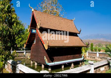 Il Wat Puttha En (วัดพุทธเอ้น) è un tempio tipicamente tailandese del nord, fondato nel 1868. E 'soprattutto notevole per il suo piccolo, bot nam (โบสถ์น้ำ) in legno o sala di ordinazione, costruito in cima a pilastri nel centro di una piazza stagno di loto. Tali ‘cappelle d’acqua’ sono rare in tutta la Thailandia. Il viharn recentemente rinnovato è attraente ma non notevole, ma dietro, su pali di legno rosso etiolated, si trova un ho mai (biblioteca di scrittura) di stile nord, decorato con motivi di lai kram rossi e dorati. Nascosto in una stretta valle, Mae Chaem (แม่แจ่ม) deve essere uno degli angoli meno accessibili di Chiang mai. Foto Stock